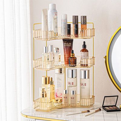 a gold shelf with various beauty products on it and a round mirror in the background