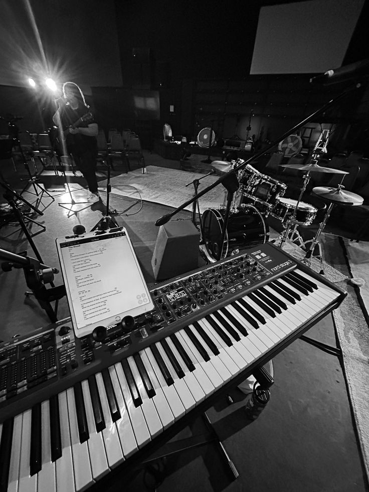 an electronic keyboard sitting on top of a table in front of microphones and drums