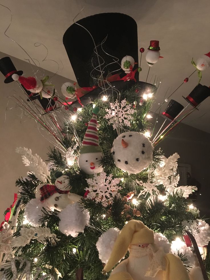 a christmas tree decorated with snowmen and other holiday decorations, including santa's hat