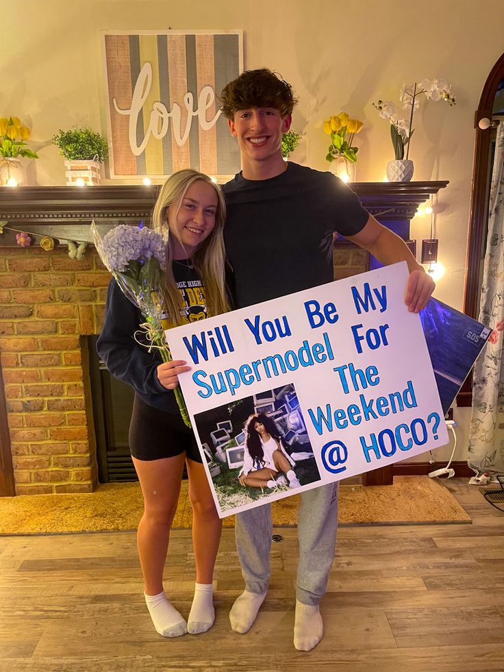 a man and woman standing next to each other in front of a sign that says will you be my supermodel for the weekend @ hoo?