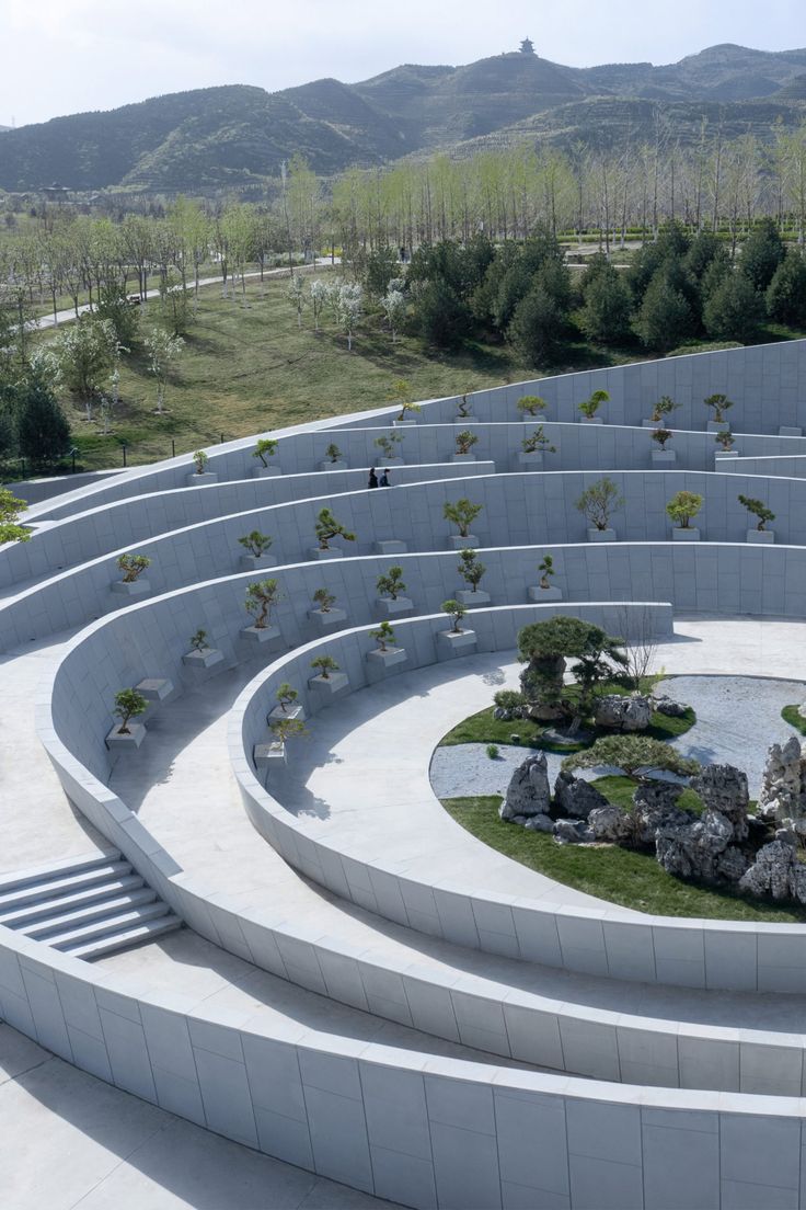 an aerial view of a circular concrete structure with trees and rocks in the center,