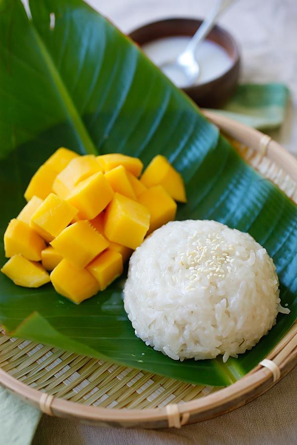 a plate with rice, mango and coconut on it next to a green banana leaf