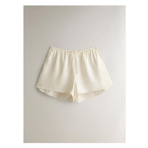 Plain-colored silk shorts with a tie at the waist for adjusting. Mulberry silk is characterized by its lightness, softness and uniform color. It is also a heat-regulating fabric, which makes the winter mild and the summer cool, ideal for use in items that are in direct contact with the skin. Beige Short Beachwear Bottoms, Solid Color High-waisted Pajama Shorts For Spring, White Silk Summer Bottoms, White Silk Bottoms For Summer, Summer Silk Cream Bottoms, Summer Cream Silk Bottoms, Cream Silk Bottoms For Summer, Beige Beachwear Shorts For Spring, Beige Beachwear Shorts