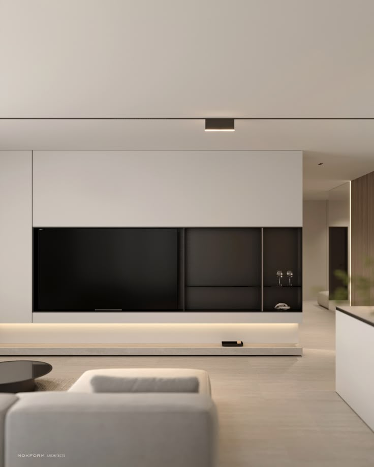 a living room with white furniture and a flat screen tv mounted on the wall above it