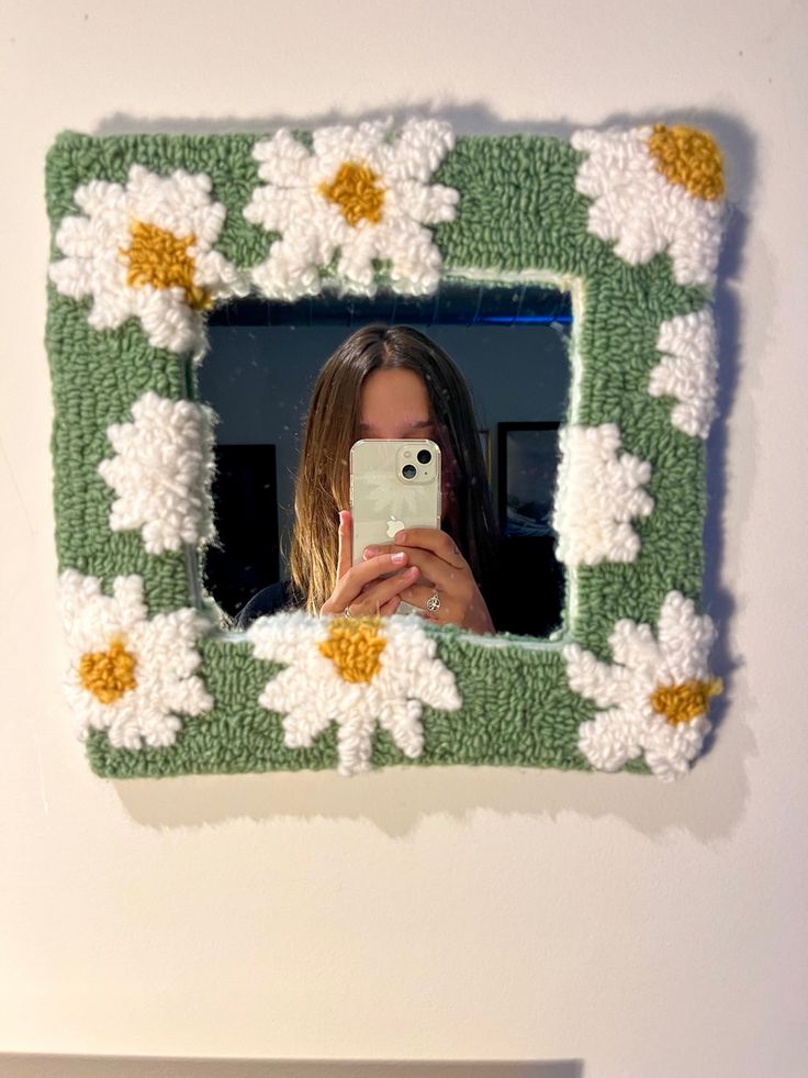 a woman taking a selfie with her cell phone in front of a flowered frame