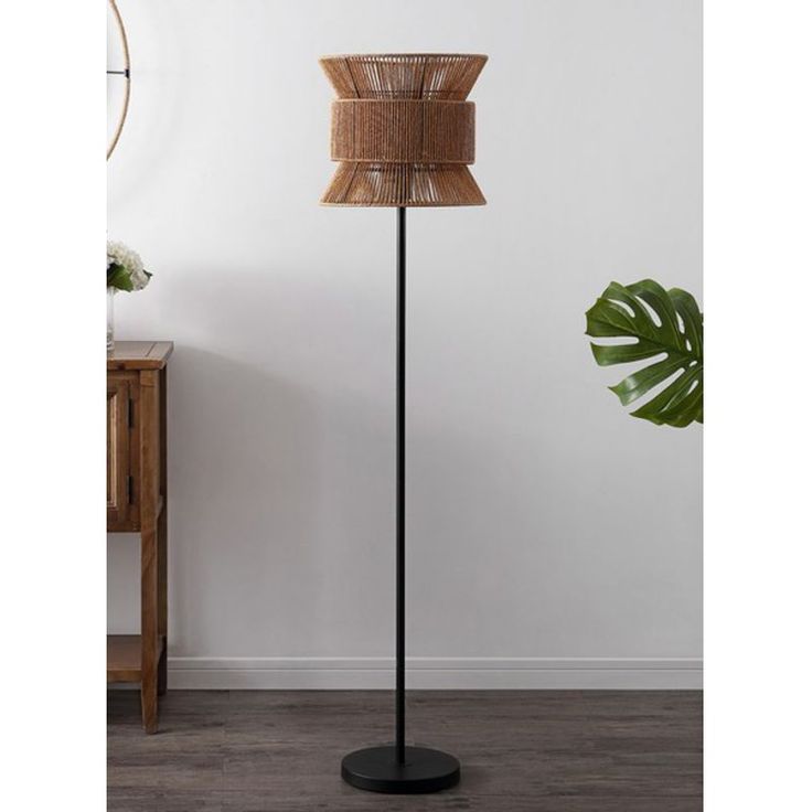 a floor lamp with a rattan shade on the top and a black metal base