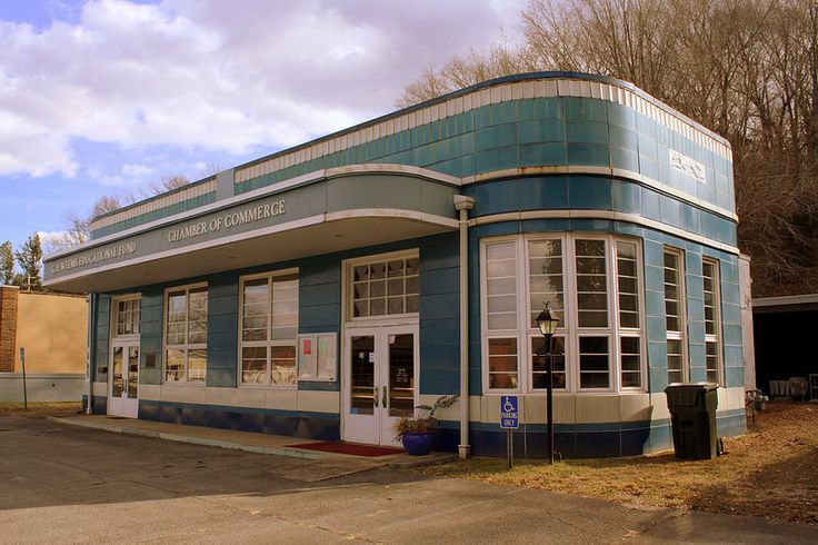 an old blue and white building sitting on the side of a road next to trees