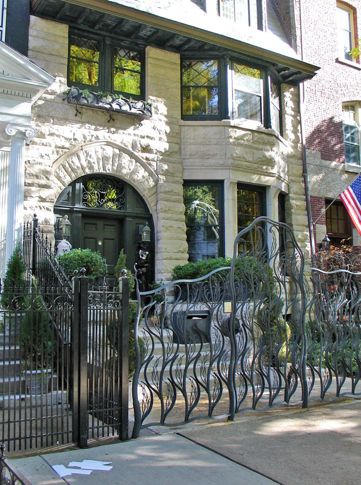 an iron gate in front of a house with american flag hanging on the side of it