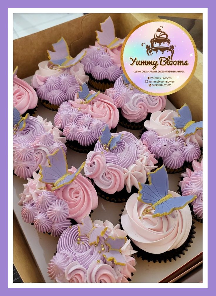 a box filled with pink and purple cupcakes on top of a table covered in frosting