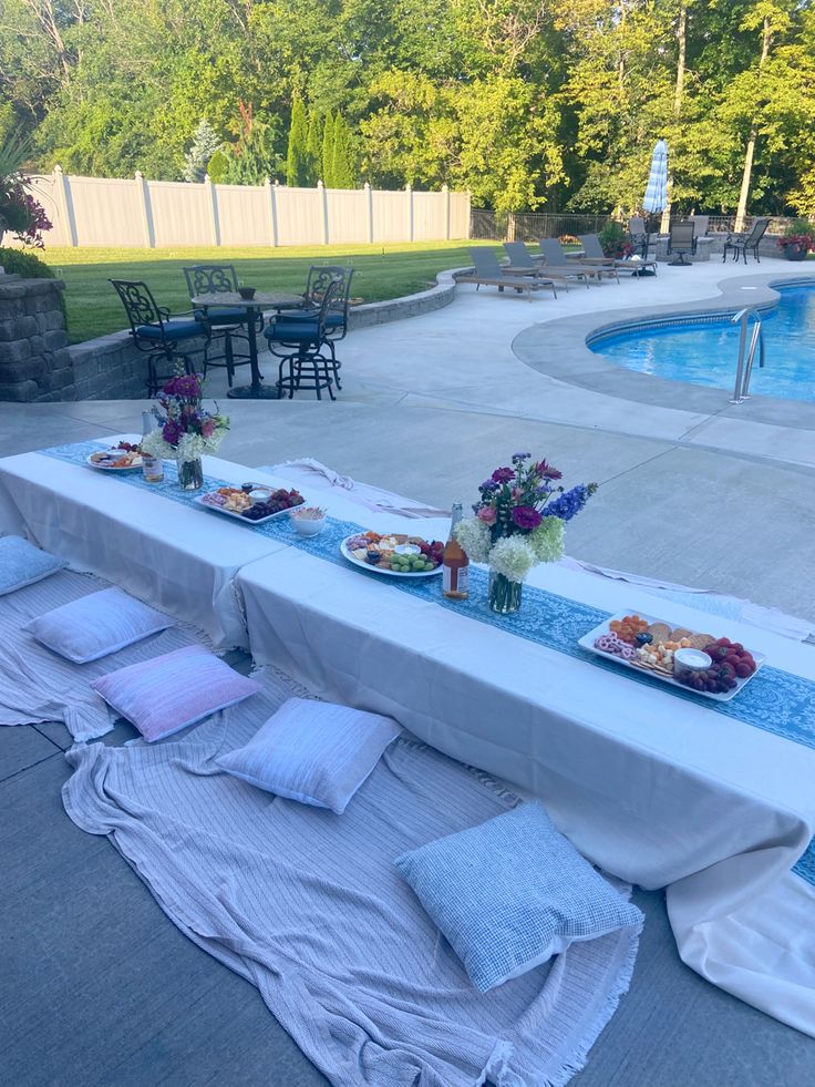 a long table with food on it next to a swimming pool