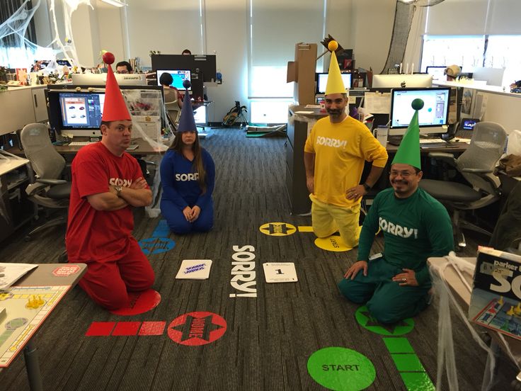 some people are dressed up and sitting on the floor in an office with many computers