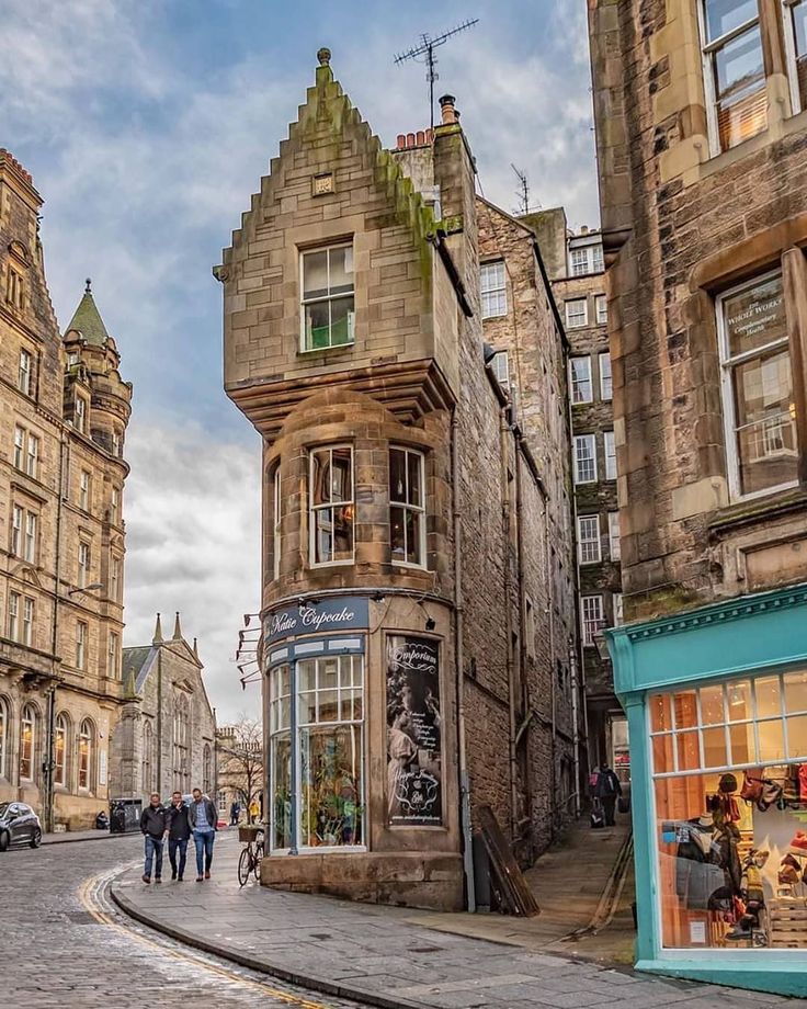 some people are walking down the street in front of old buildings with shops on each side