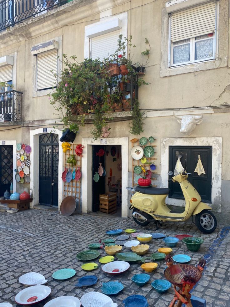 a scooter parked in front of a building with plates on the ground