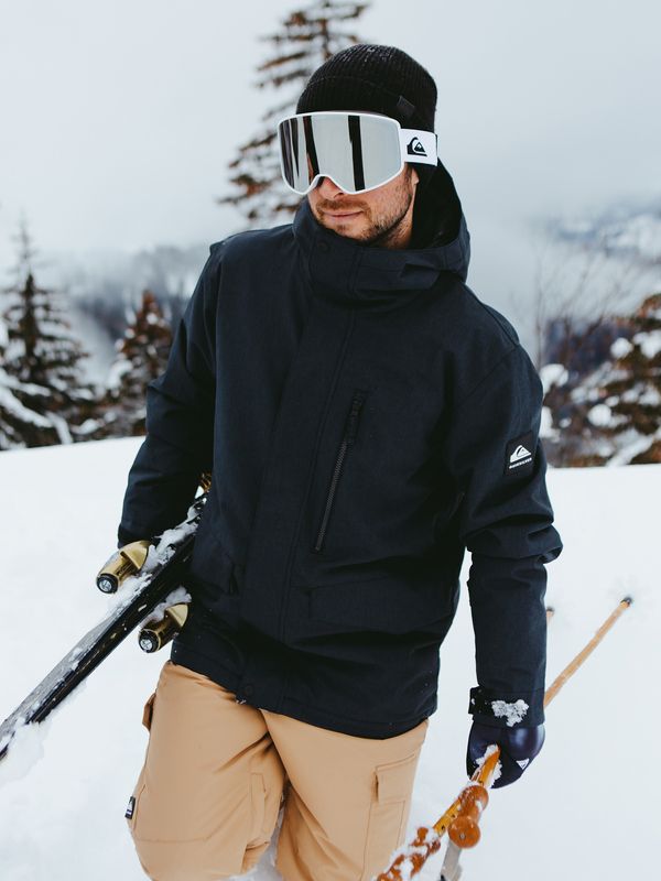 a man with skis and goggles standing in the snow