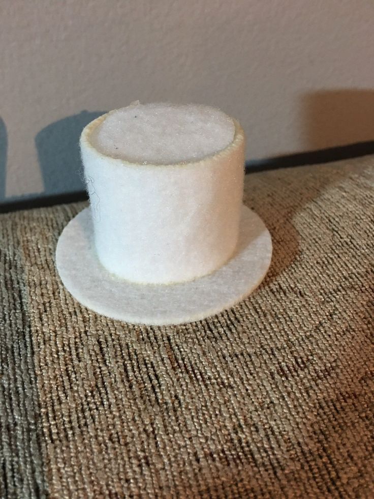 a small white hat sitting on top of a chair next to a wall and carpet