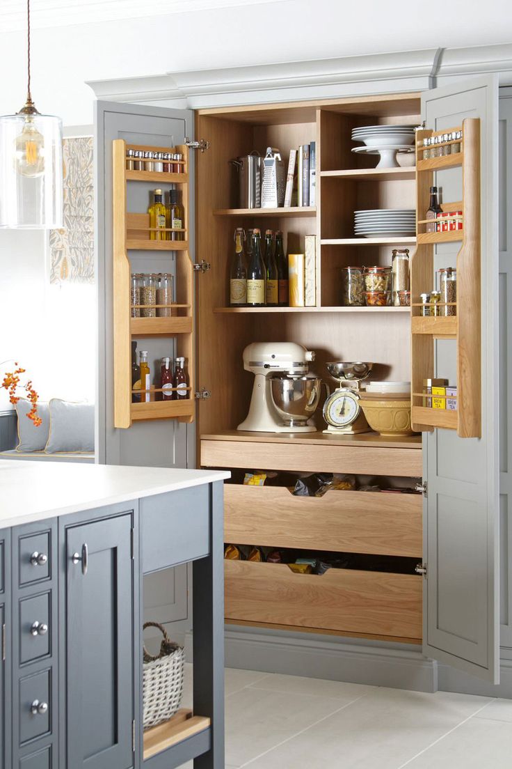 an open cabinet in the middle of a kitchen with lots of cupboards and drawers