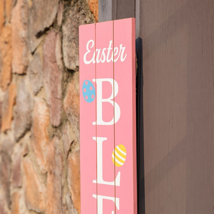 a pink sign that says easter is on the side of a brick wall next to a door