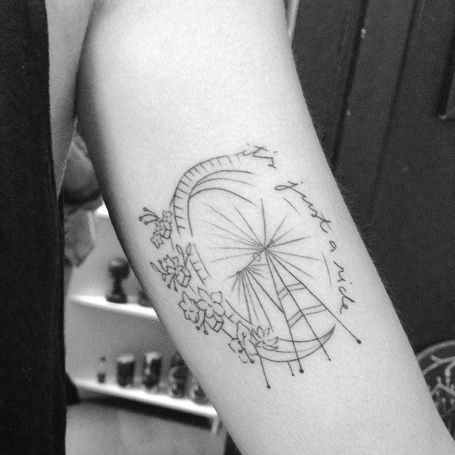 a black and white photo of a person's arm with a ferris wheel tattoo