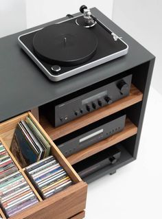 the record player is sitting on top of an entertainment center with its drawers full of cds