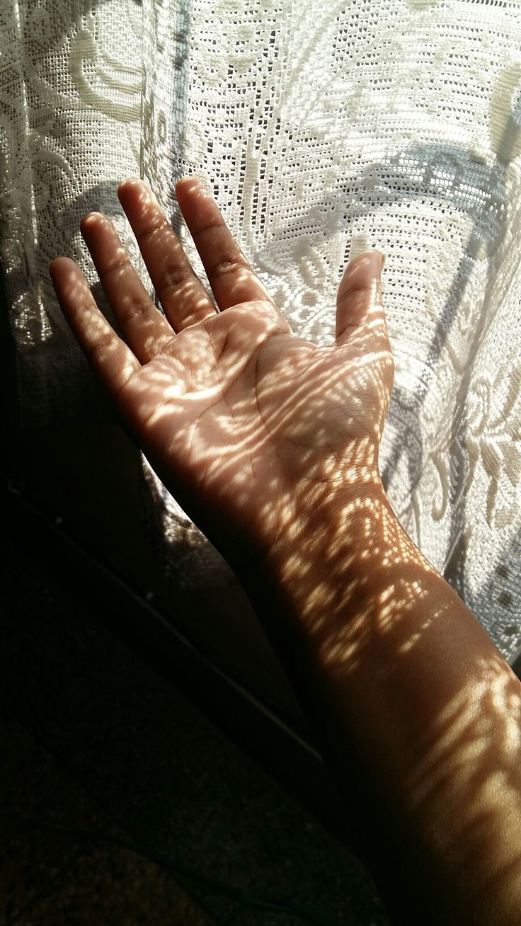 a person's hand with the sun shining on them