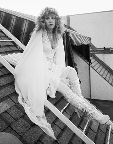 a woman sitting on top of a set of stairs wearing white clothes and high heels