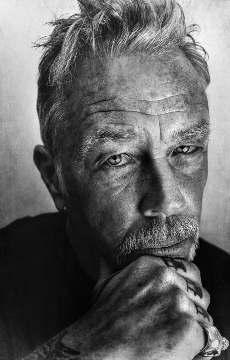 black and white photograph of an older man with his chin resting on his hand, looking at the camera