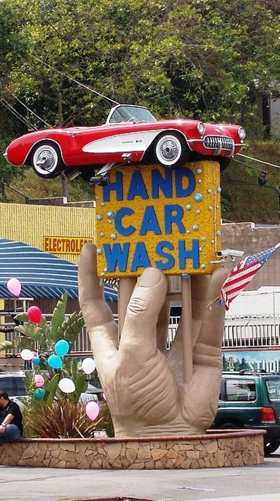 a hand holding up a sign that says hand car wash