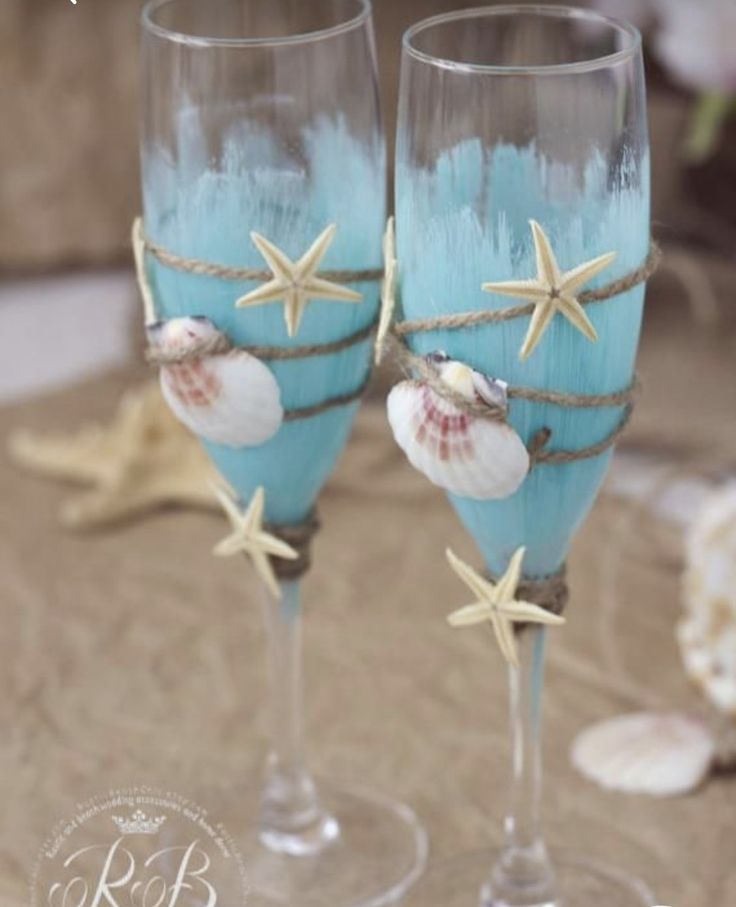 two wine glasses decorated with seashells and starfish are sitting on a table