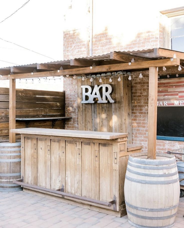 an outdoor bar with wooden barrels and lights