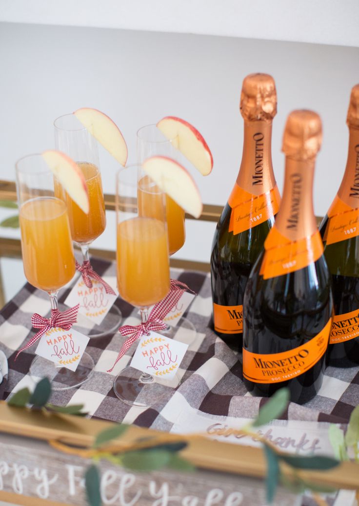 several bottles of champagne and glasses on a table with apples in the foreground,