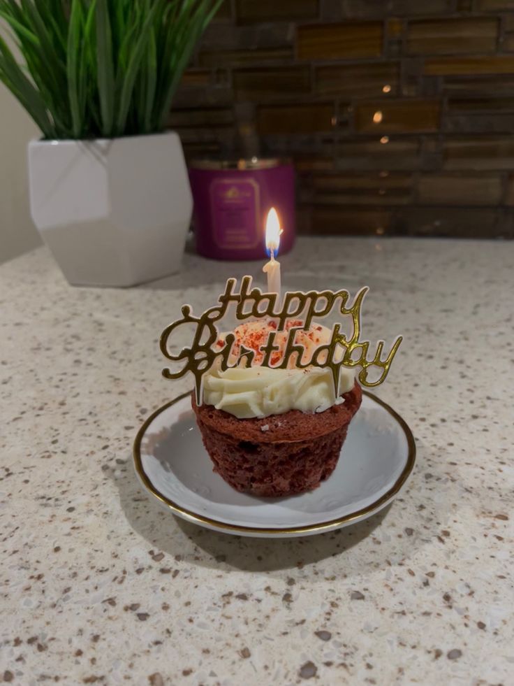 a cupcake sitting on top of a plate with a lit candle in the middle