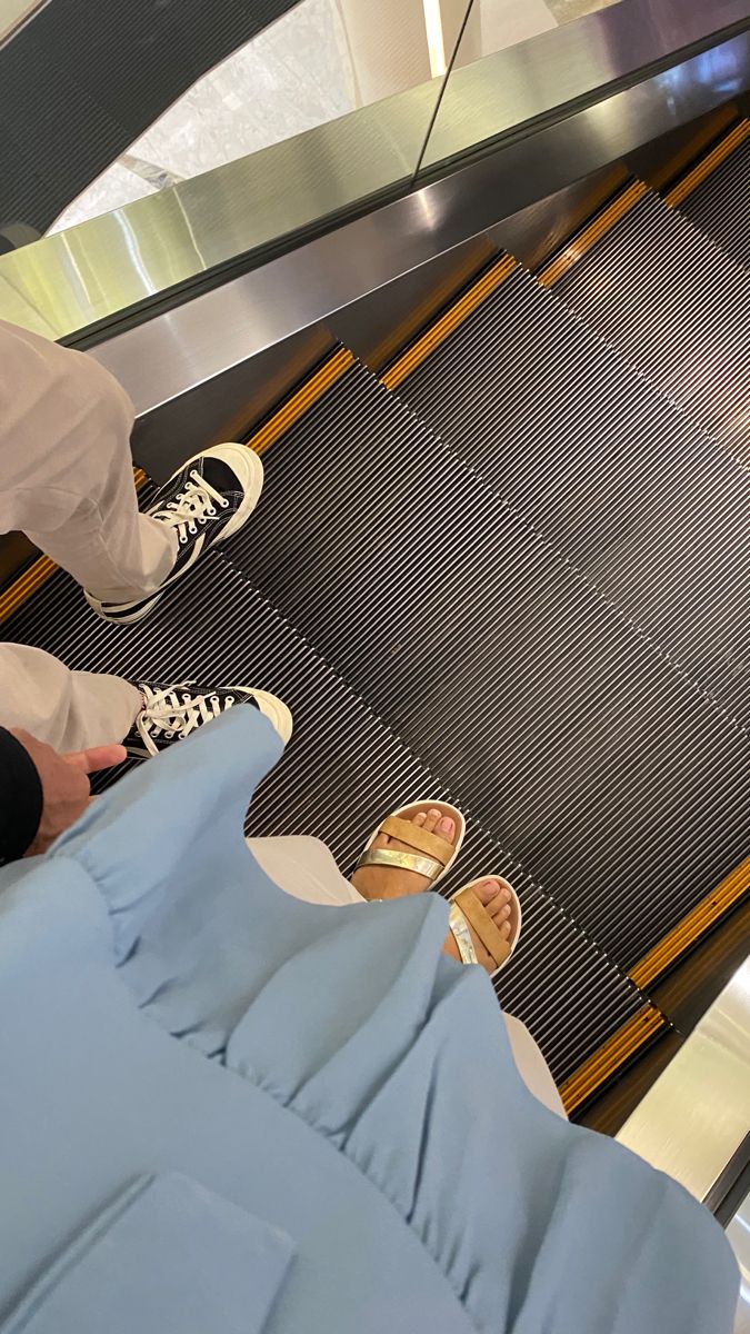 two people standing on an escalator with their feet in the air and one person wearing white shoes