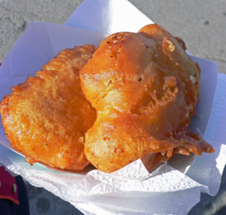 two fried food items sitting on top of a paper wrapper in someone's hand