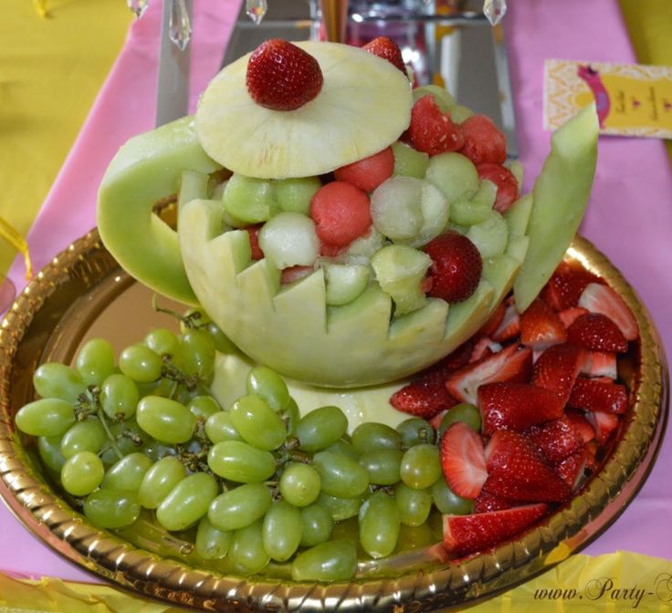 a plate with grapes, melon, and strawberries in the shape of a teapot