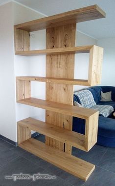 a blue couch sitting in front of a wooden book shelf next to a white wall