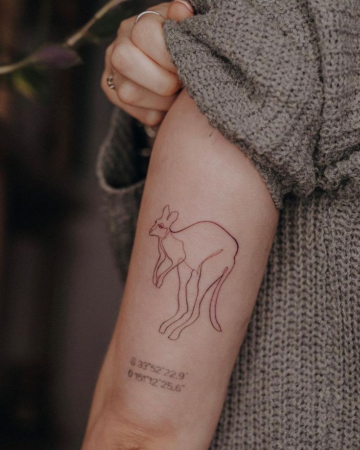 a woman's arm with a small kangaroo tattoo on the left side of her arm