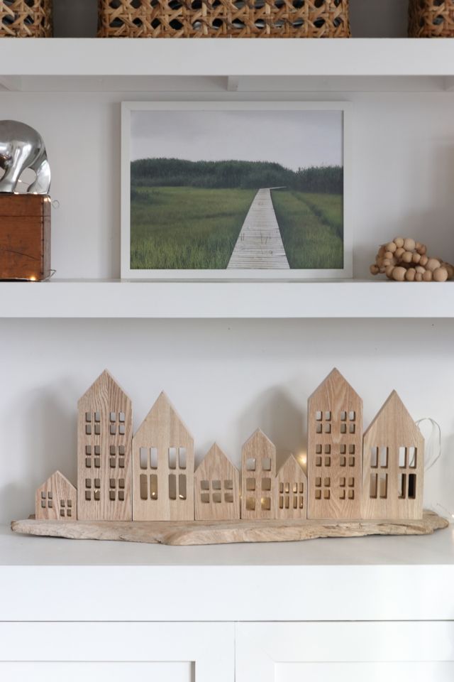 a white shelf with some wooden houses on it