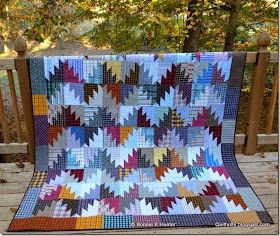 a colorful quilt is hanging on a wooden fence