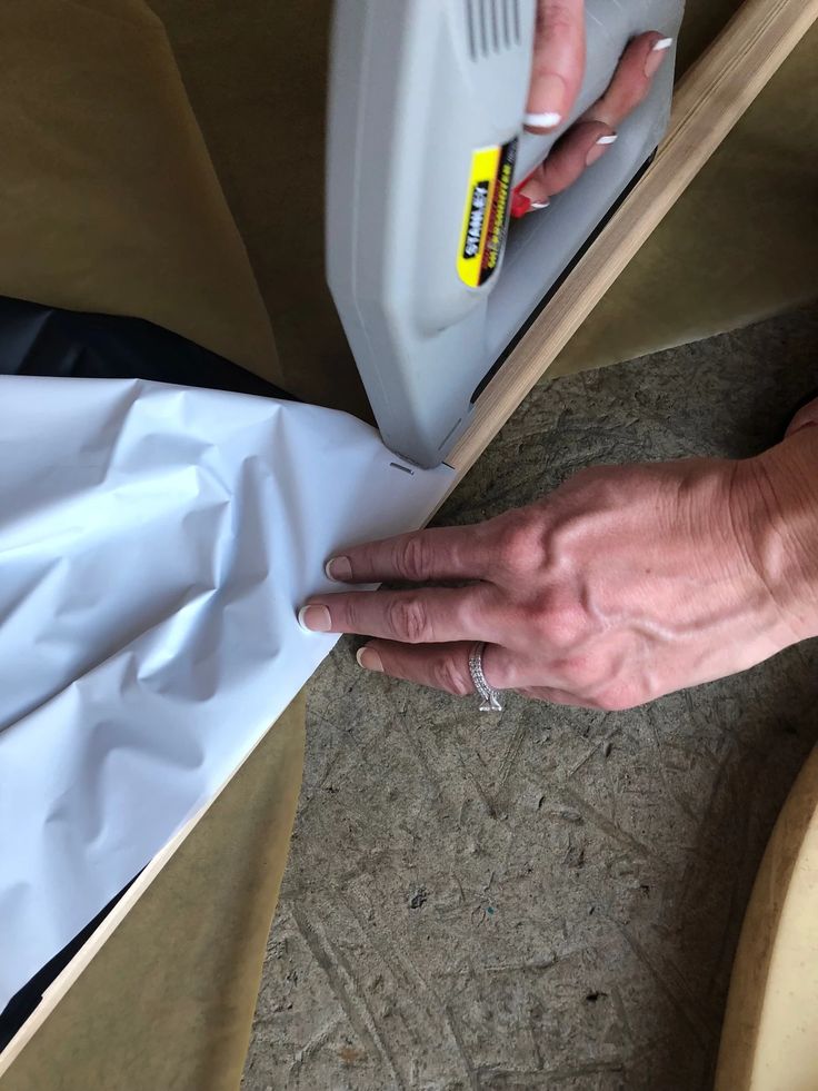 a woman's hand on top of a table next to a plastic container and paper