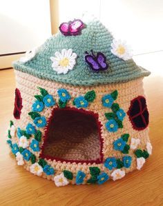 a crocheted house with flowers and butterflies on it