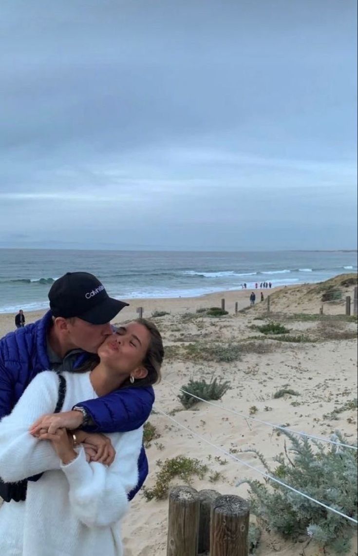 a man and woman kissing on the beach