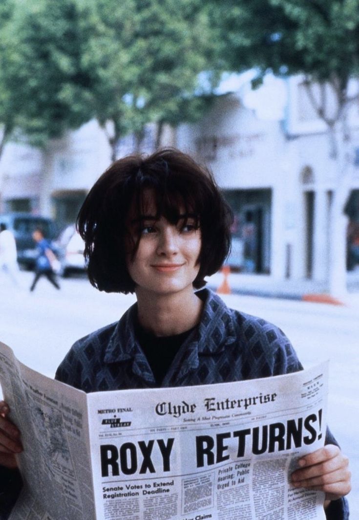 a woman holding up a newspaper while standing on the street