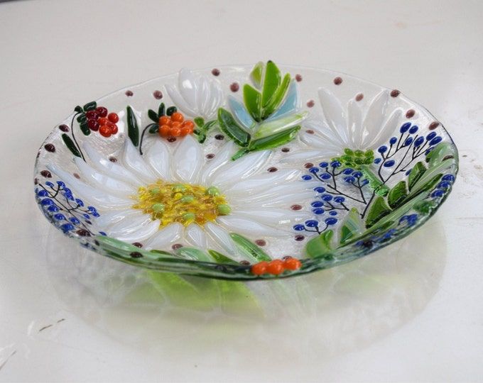 a glass bowl with flowers and leaves painted on it