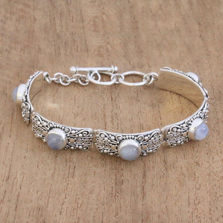 Five sterling silver arced rectangles embellished with swirl and dot motif are linked together in this wristband bracelet. Each rectangle holds a cabochon of rainbow moonstone at its center. Artisan Buana of Bali handcrafts this lovely bracelet. Bohemian Silver Moonstone Bracelets, Silver Bohemian Moonstone Bracelets, Adjustable Elegant Sterling Silver Bracelet With Moonstone, Adjustable Elegant Sterling Silver Moonstone Bracelet, Elegant Adjustable Sterling Silver Moonstone Bracelet, Pearl Cocktail Ring, Silver Link Bracelet, Faceted Gems, Wristband Bracelet