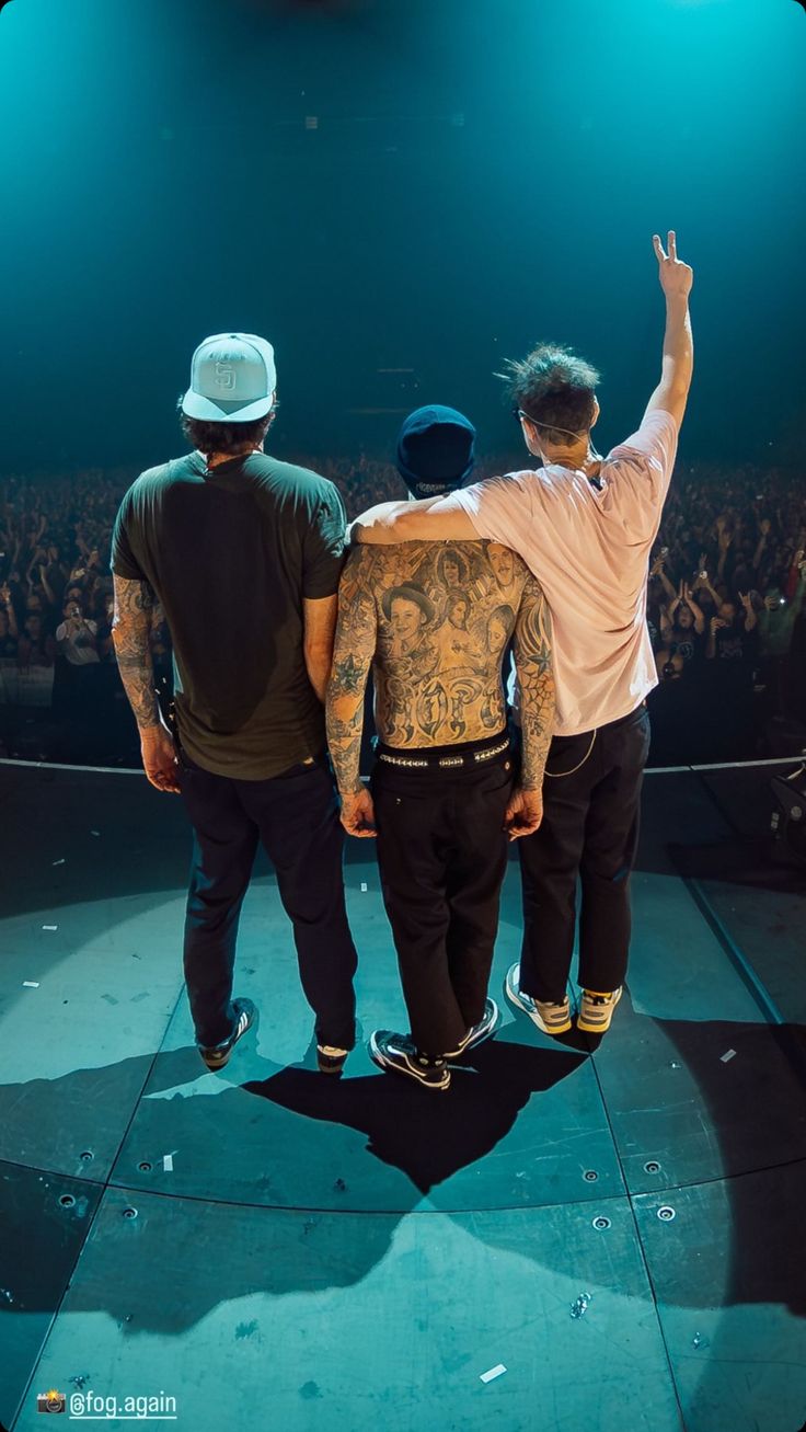 three men standing on top of a stage with their arms in the air