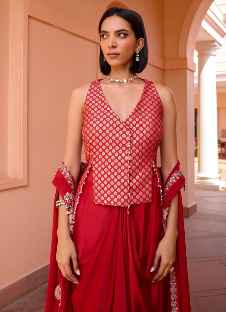 Elevate your wardrobe with this exquisite Red Embroidered Skirt Set, crafted from luxurious chanderi jacquard. The vibrant red blouse, adorned with intricate embroidery, exudes sophistication and style, making it perfect for festive occasions and special gatherings. Paired with a flowing skirt that drapes elegantly, this ensemble creates a flattering silhouette, blending traditional craftsmanship with contemporary design for a look that is both timeless and captivating. Style it with a layered c Red Cotton Silk Sharara With Cutdana, Red Cotton Silk Sharara With Cutdana Details, Red Cotton Silk Sharara With Traditional Drape, Red Semi-stitched Cotton Silk Sharara, Red Traditional Cotton Silk Sharara, Traditional Red Cotton Silk Sharara, Red Cotton Silk Sharara For Diwali, Bollywood Style Red Cotton Silk Sharara, Elegant Brocade Pre-draped Saree For Designer Wear