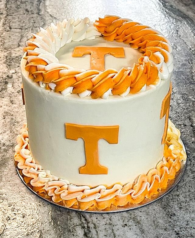 a cake with the letter t on it sitting on top of a marble countertop