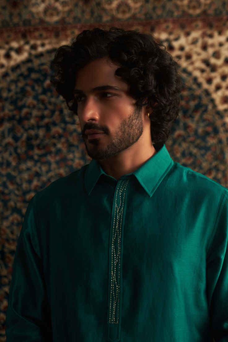 This emerald green pathani kurta set is a stunning choice for festive occasions like mehendi. The subtle embroidery on the placket adds a touch of elegance without being over the top. Paired with a coordinating salwar in a color-on-color design, it strikes the perfect balance between traditional and stylish. This set is sure to become a go-to piece in your wardrobe for celebrating special moments! Green Sherwani With Zari Work Straight Kurta, Green Sherwani With Zari Work, Straight Kurta Style, Green Sherwani With Zari Work, Green Chanderi Sherwani For Diwali, Green Chanderi Sherwani With Traditional Drape, Green Chanderi Sherwani For Eid, Green Sherwani With Mirror Work For Eid, Festive Green Chanderi Bandhgala, Green Embroidered Chanderi Bandhgala