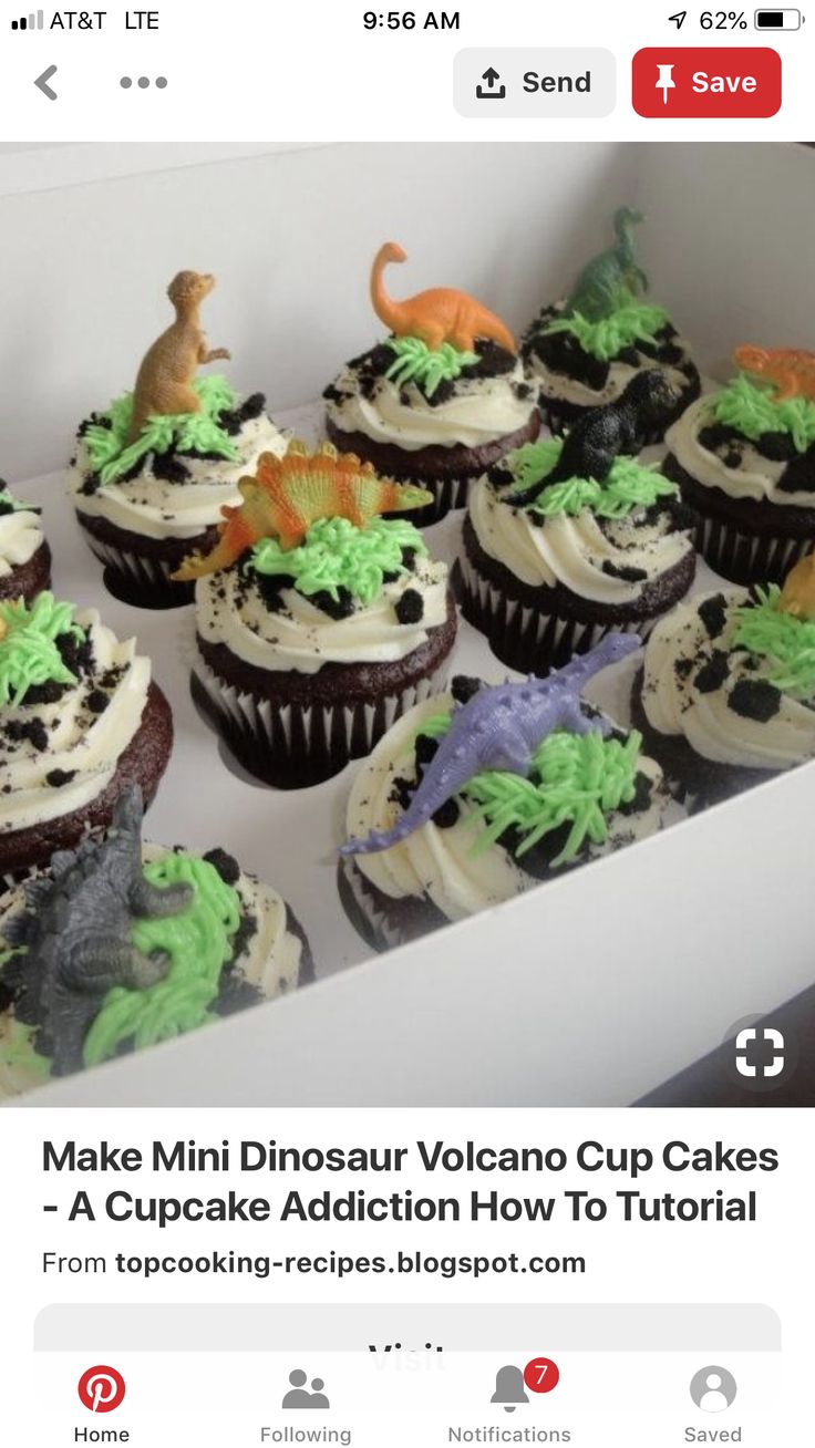 there are many cupcakes in the box with dinosaur decorations on them and frosting