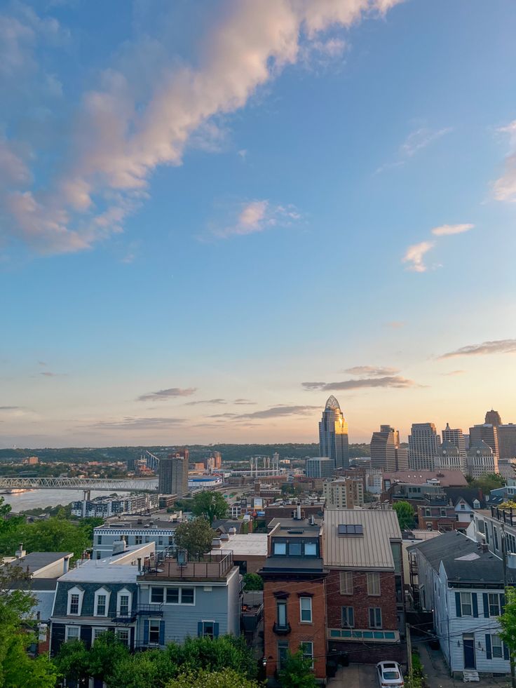 an aerial view of a city with tall buildings and the sun setting in the distance